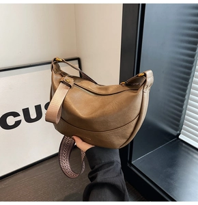 Détail d'un sac demi-lune en similicuir marron avec une large bandoulière tissée chevron