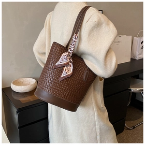 Detail of dark brown woven leather bucket bag with decorative geometric silk scarf handle
