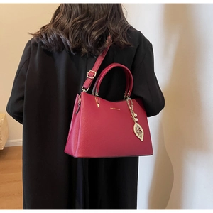 Close-up of deep red textured leather handbag with gold leaf and pearl charm detail