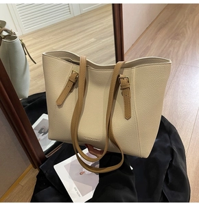 Détail du cabas en cuir beige texturé avec bandoulière marron et texte embossé