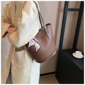 Detail of dark brown woven texture bucket bag featuring a decorative patterned silk scarf
