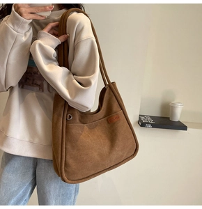 Detail of a dark brown suede tote bag featuring a practical outer pocket and vintage texture