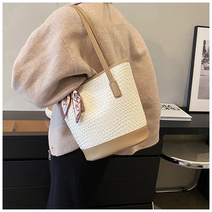 Close-up of white woven bucket bag with khaki trim and geometric silk scarf detail