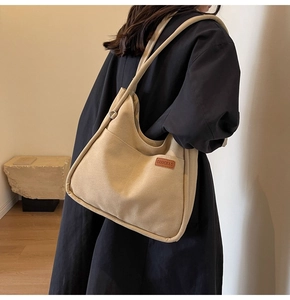 Close-up of a high-quality beige canvas tote bag with a brown leather logo tag detail