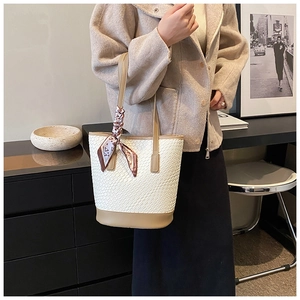 Detail of cream woven bucket bag with khaki leather trim and patterned silk scarf accessory
