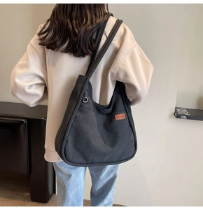 Detailed view of black canvas bucket bag with brown leather patch on model