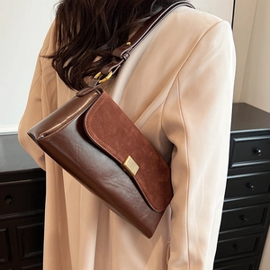 Brown vintage faux suede underarm bag with gold buckle on a model in pink suit
