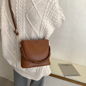 Sac seau en cuir marron avec poignée tressée et bandoulière réglable sur modèle