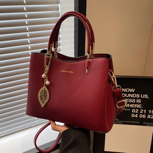 Elegant red litchi grain leather handbag with gold leaf charm and pearl detail