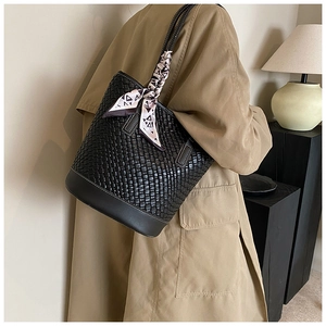 Detail of a black woven leather bucket bag featuring decorative geometric silk scarf