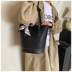 Close-up of woven black leather tote bag featuring a geometric silk scarf on the handle