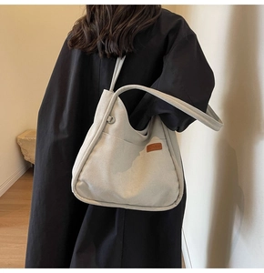 Detail of grey large capacity canvas bucket bag with leather logo tag on model