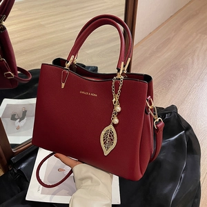 Elegant red leather handbag with gold leaf charm and top handle for wedding events