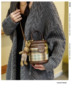 Détail du sac seau en laine à carreaux avec breloque lapin porté sur un gilet en maille