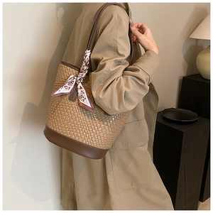 Detail view of a camel woven bucket bag with silk scarf and dark brown leather base