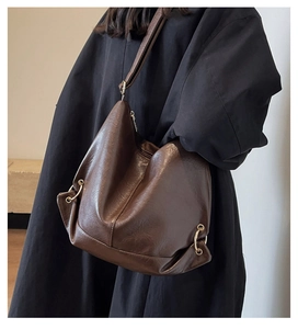 Detail of a large brown leather tote bag with gold metal ring and retro soft design