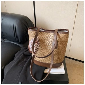 Close-up of woven bucket bag with dark brown leather straps and a decorative silk scarf