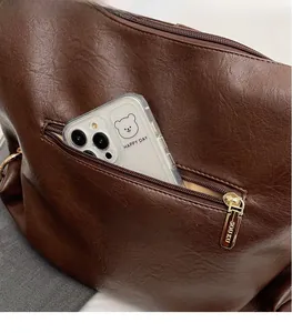 Detail of dark brown faux leather tote with functional rear zipper pocket and storage space