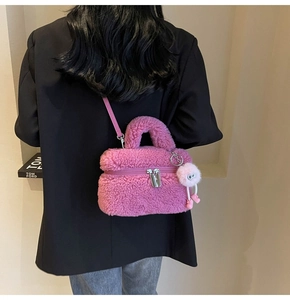 Sac seau en peluche rose avec pendentif pompon porté à l'épaule par un mannequin