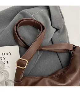 Detail of adjustable shoulder strap with gold buckle on dark brown lychee leather bag