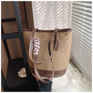 Detail of woven tote bag with brown leather base and decorative silk scarf handle