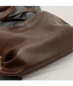 Close-up of brown PU leather tote showing fine grain texture and gold metal ring detail