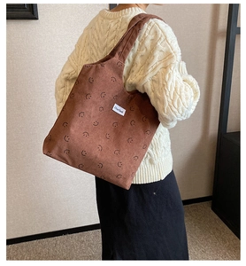 Détail du sac cabas en velours côtelé marron avec motifs sourire et étiquette