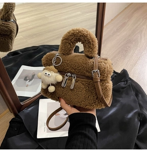 Détail de sac seau en peluche marron avec bandoulière en cuir et pendentif agneau