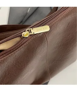 Detail of dark brown leather texture and premium gold-tone SOU KU zipper hardware