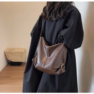 Close-up of deep brown leather tote bag with subtle grain and gold ring hardware