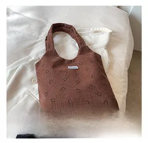 Gros plan du sac cabas en velours côtelé marron avec motifs sourires et étiquette