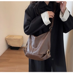 Detail of a brown leather Hobo bag featuring a gold metal ring and soft texture finish