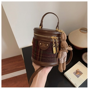Détail du sac cylindre vintage en tissu écossais rouge et vert avec charms dorés