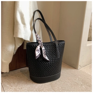 Detail of black woven bucket bag with silk scarf and large interior capacity