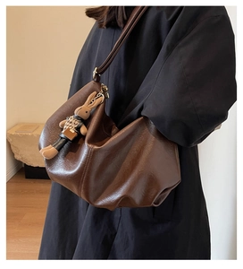 Detail of soft brown pleated tote bag featuring smooth faux leather and a cute bunny charm