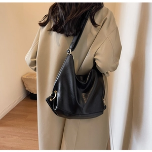 Close-up of a large black soft leather hobo bag worn with a khaki trench coat