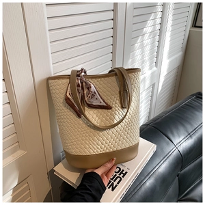 Close-up of woven bucket bag featuring khaki leather trim and silk scarf accessory