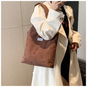 Gros plan d'un sac cabas en velours côtelé marron avec imprimé smiley et manteau