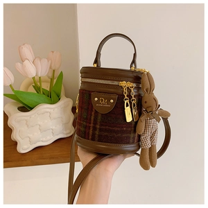 Détails de couture en cuir marron et tissu à carreaux vert sur le sac seau chic