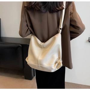 Model wearing a large cream PU leather tote bag with elegant gold metal ring detail