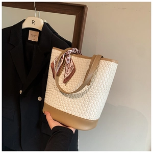 Detail of woven bucket bag featuring a silk scarf handle and leather patchwork design