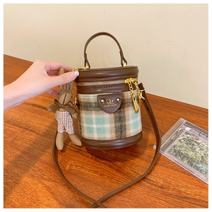 Détail du sac seau à carreaux avec bordure en cuir et charm peluche lapin mignon
