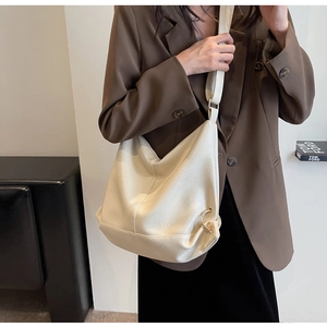 Detail of soft cream PU leather tote with wide strap and gold ring hardware in a casual setting