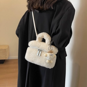 Sac seau en polaire blanche avec breloque agneau porté par un mannequin en manteau