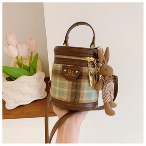 Détail du sac seau en tweed à carreaux avec finitions cuir et pendentif lapin mignon