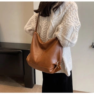 Brown hobo shoulder bag with large capacity and gold ring detail shown on a model