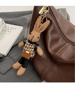 Close-up of a handmade brown knitted rabbit bag charm with a stylish houndstooth vest