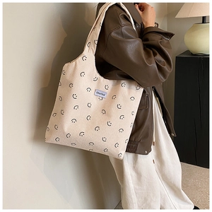 Détail du sac cabas en velours côtelé beige avec motif smiley et étiquette violette