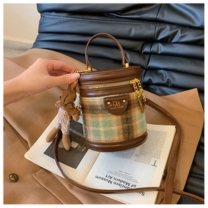 Détail du sac cylindre en cuir marron et tissu à carreaux avec charm lapin en peluche