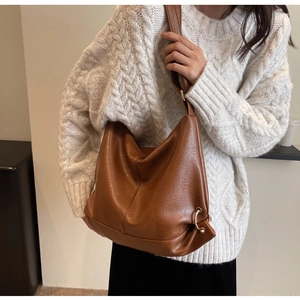 Detail of a large brown PU leather hobo bag with a wide strap shown on a model